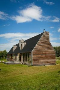 a large wooden barn with a black roof on a field at Architect-Designed House With Views In Uckermark in Gerswalde +10 photos