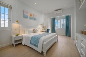 a white bedroom with a large bed and windows at The Salt Villas Da Nang - 250sm 3BR, 4BA & Kitchen in Danang