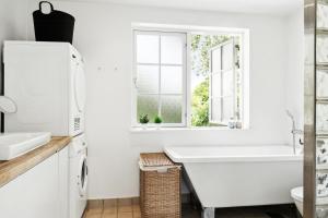 a white bathroom with a tub and a sink and a window at Family Idyll Near Kikhavn Beach in Kikhavn
