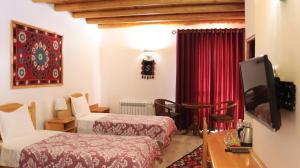 a hotel room with two beds and a television at Bibikhanum Hotel in Samarkand