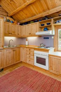 a kitchen with wooden cabinets and a white stove top oven at Historic Log Cabin By Rondane National Park in Lårgard +20 photos