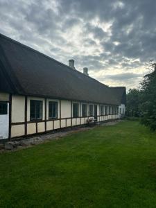 Un edificio blanco con techo negro y un patio verde. en Historic Skipper Farm Near Nordby Hills And Beach, en Nordby