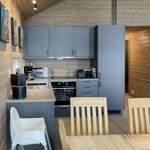 a kitchen with white cabinets and a table and chairs at Modern Cabin With Panoramic View On Bringsfjellet in Lalm