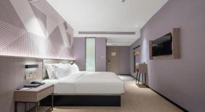 WuzhouにあるBorrman Hotel Wuzhou College Fumin Roadの大きな白いベッドとテレビのある寝室