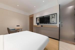 a hotel room with a bed and a tv on the wall at City Comfort Inn Jingzhou Fantawild Shashi Middle School in Shashi