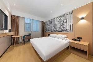 a hotel room with a large white bed and a desk at City Comfort Inn Jingzhou Fantawild Shashi Middle School in Shashi