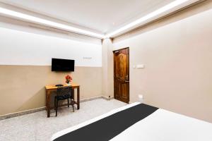 a room with a bed and a desk and a television at Collection O White Town in Puducherry +21 photos