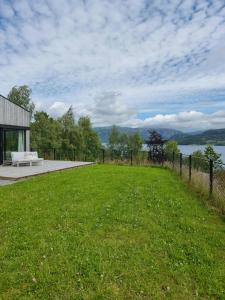 a grassy field with a bench in front of a building at Cabin By The Fjord With Rooftop Terrace On Randøy in Hjelmeland
