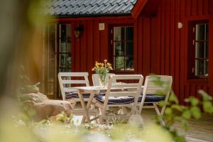 a table and chairs with a vase of flowers on a patio at Quaint Barn Nestled Between Sea And Forest in Båstad +9 photos