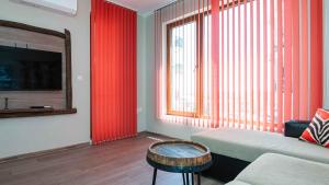 a living room with red curtains and a couch and a table at Flat Lora Pomorie in Pomorie