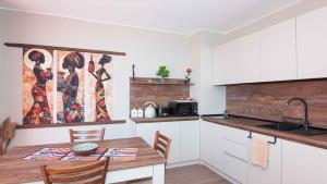 a kitchen with a wooden table and a kitchen with white cabinets at Flat Lora Pomorie in Pomorie