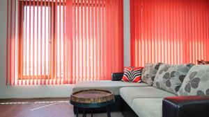a living room with red curtains and a couch and a table at Flat Lora Pomorie in Pomorie