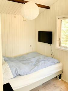 a bedroom with a bed with a tv on the wall at Charming Beach Cottage In Gilleleje in Gilleleje