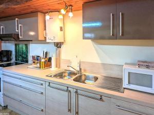 a kitchen with a sink and a microwave at Charmante maison de village en Haute-Saône avec cheminée - FR-1-583-479 in Morey +16 photos