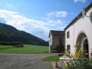 a white building with a field in the background at Gîte de charme à Saint-Bresson, proche activités nature - FR-1-583-476 in Saint-Bresson
