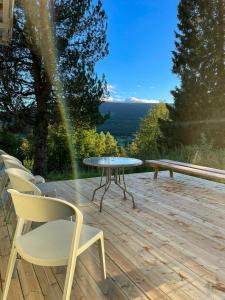 eine Terrasse mit einem Tisch und Stühlen auf einer Holzterrasse in der Unterkunft Historic Old Rectory In The Heart Of Norway in Vestre Gausdal