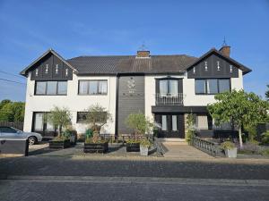 a white house with a black roof at Lazy Olives in Tongeren