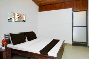 a bedroom with a bed with white sheets and a window at Collection O Malavli Lonavala Hill View in Lonavala