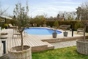 una piscina in un cortile con due alberi in vasi di Bright Summer House With Pool In Tisvildeleje a Tisvildeleje