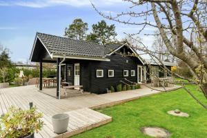 una piccola casa nera con terrazza in legno di Bright Summer House With Pool In Tisvildeleje a Tisvildeleje