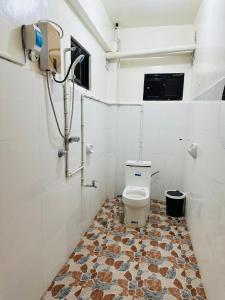 a bathroom with a toilet and a tiled floor at Brklyn Homestay in Banaue