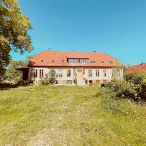 an old house with a red roof on a field at Cozy Holiday Apartment In The Manor House in Rambin