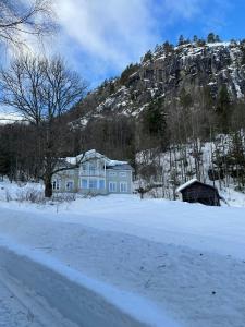 a house in the snow in front of a mountain at Charming Farm From 1600S In Stunning Surroundings in Treungen