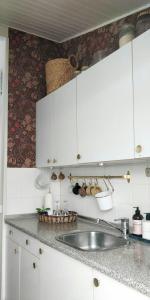 a kitchen with white cabinets and a sink at Victorian Summer House On Beautiful Natural Plot in Rønde