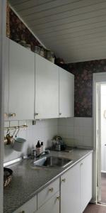 a kitchen with white cabinets and a sink at Victorian Summer House On Beautiful Natural Plot in Rønde +15 photos