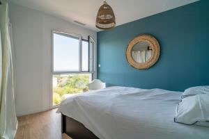 ein blaues Schlafzimmer mit einem Bett und einem Spiegel in der Unterkunft Villa With Panoramic Views Of Thau Lagoon in Bouzigues + 32 Fotos