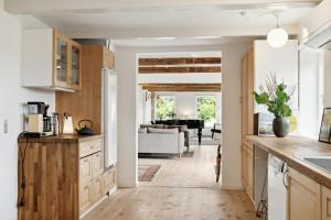 a kitchen with white cabinets and a living room at Renovated Estate With Private Beach in Roslev