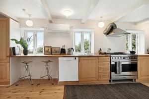 a kitchen with wooden cabinets and white appliances at Renovated Estate With Private Beach in Roslev