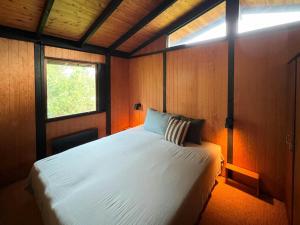 Un dormitorio con una cama blanca con una ventana. en Original 70S Home Surrounded By Woods, en Vejby