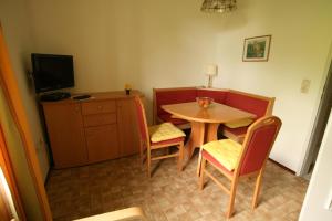 Kleines Zimmer mit einem Tisch, Stühlen und einem TV. in der Unterkunft Pension Seevilla Annelies in Maria Wörth