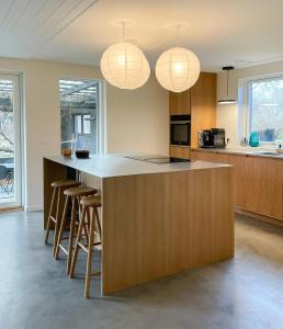 Una cocina con una gran isla con taburetes de bar. en Summer House Charm Near The Beach And Rågeleje, en Vejby