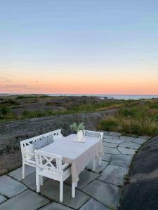 a white table and two white benches sitting on a stone patio at Charming Holiday Home By Sea Near Stavern in Stavern