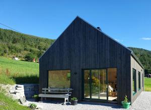 a black house with a bench in front of it at Architect-Designed Cabin With Beach Nearby in Lensvik
