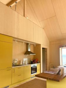 a kitchen with yellow cabinets and a wooden table at Architect-Designed Cabin With Beach Nearby in Lensvik