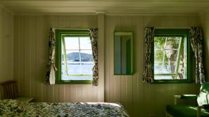 a bedroom with two windows and a bed at Cabin With Sunset Views And Private Dock in Sandefjord