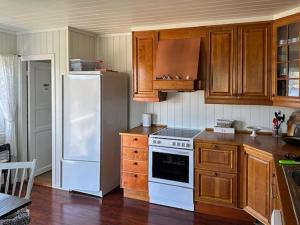 a kitchen with a white refrigerator and wooden cabinets at Explore Håøya Nature Reserve in Helgeroa