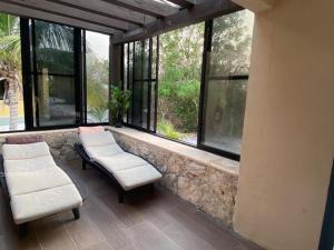 a balcony with two chairs and a bench and windows at Matraca 74 in Celestún