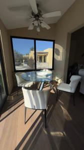 a dining room with a glass table and white chairs at Matraca 74 in Celestún