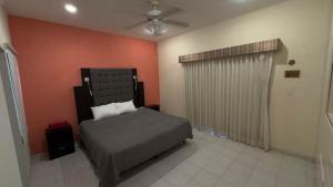 a bedroom with a bed and an orange wall at Matraca 74 in Celestún