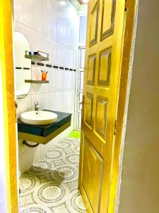 Un baño con una puerta amarilla y un lavabo. en V & V BnB, en Dar es Salaam