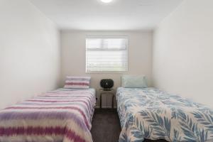 two beds in a room with white walls and a window at Maraetai Yacht Club in Maraetai