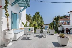 a patio with white furniture and potted plants at Le Petit Bati Blue in Skopelos Town