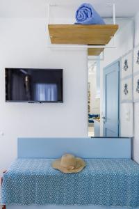 a hat sitting on top of a bed with a tv at Le Petit Bati Blue in Skopelos Town