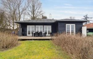 ein kleines schwarzes Haus mit einer Veranda und einem Garten in der Unterkunft Beachfront Summerhouse With Amazing View And Peace in Hesselager