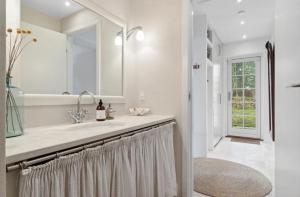a white bathroom with a sink and a mirror at Beachfront Summerhouse With Amazing View And Peace in Hesselager +20 photos
