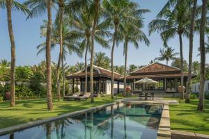a villa with a swimming pool and palm trees at Four Seasons The Nam Hai, Hoi An, Vietnam in Hoi An